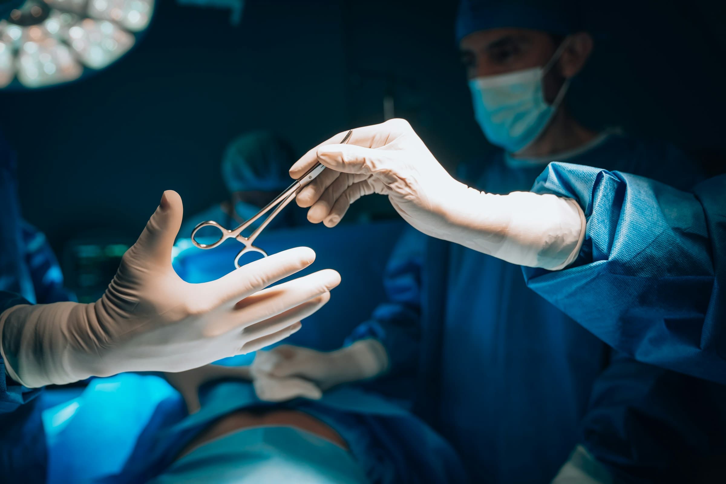 Mâini cu mănuși predând un instrument chirurgical de precizie